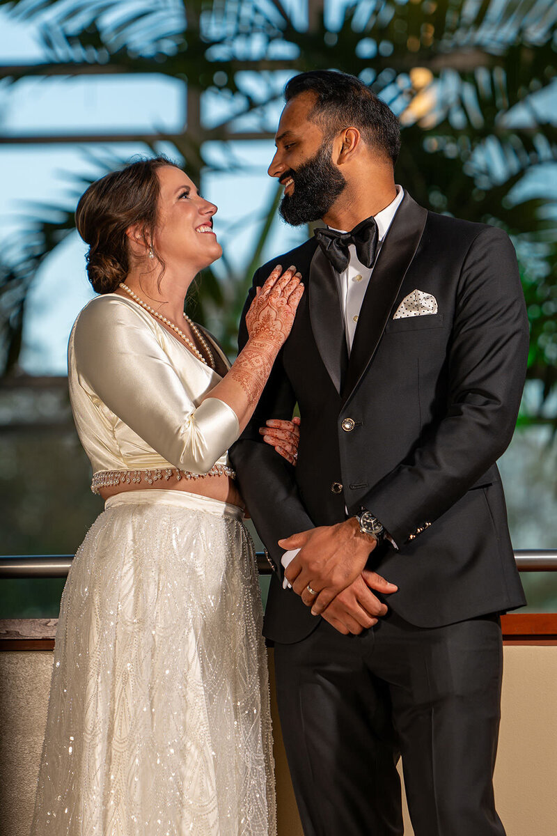 A newlywed couple with their arms linked laughing with each other 