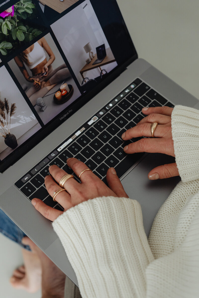 kaboompics_woman-in-white-sweater-gold-rings-jewelry-jeans-laptop-work-29437