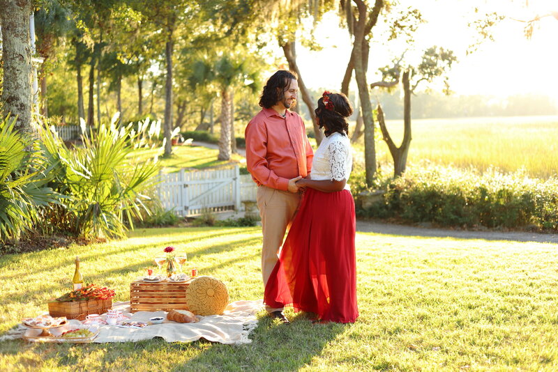 Interracial couple celebrating their anniversary with a boho styled picnic by the marsh in Mount Pleasant South Carolina at golden hour