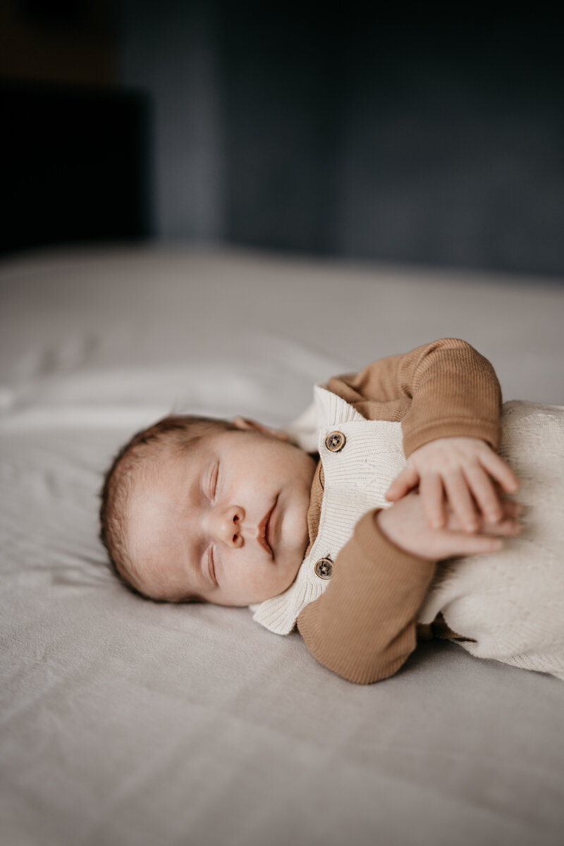 Pasgeboren baby ligt te slapen op bed tijdens een newbornshoot in Utrecht.
