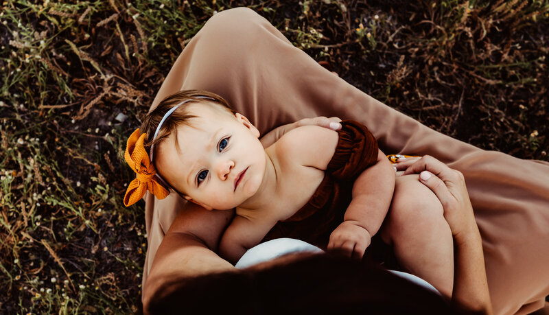 baby girl looking at the  camera on mamas laps,