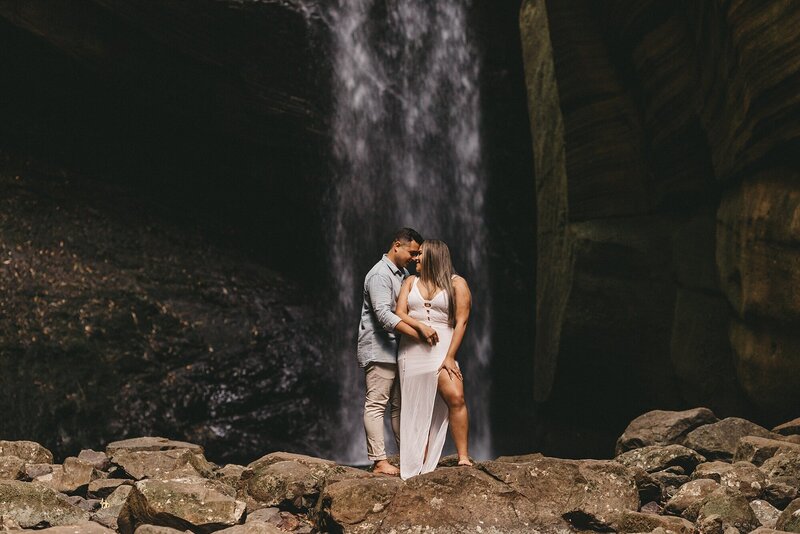 bride and groom pose by waterfall in Bali