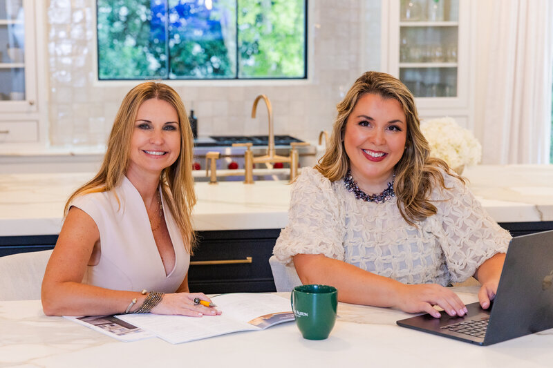 women realtor team sitting at a kitchen countertop and working in front of laptop during brand photoshoot Laure Photography