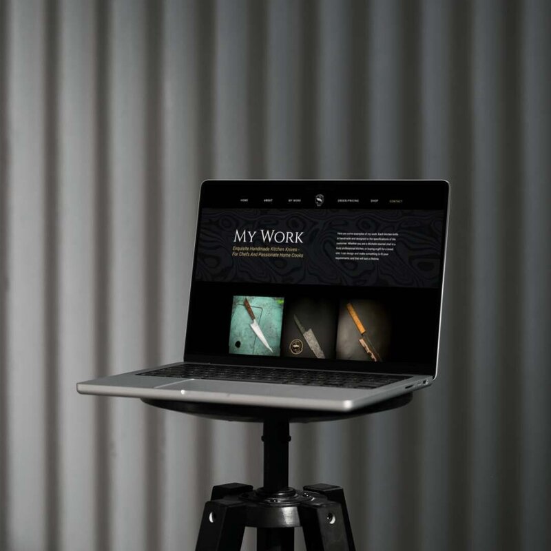 Laptop on stand, showing website page 'my work' with featured products