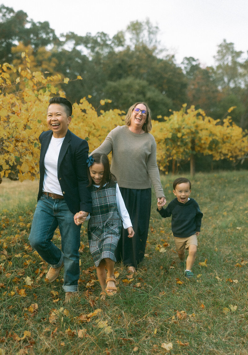 A cute mixed race family walk through a field at Hyde Park during the colorful fall season.