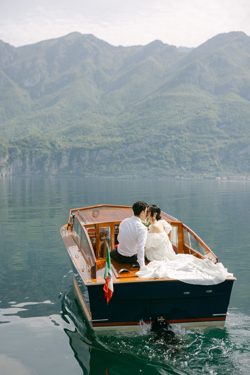 a bride and groom kissing during a boat ride in Italy