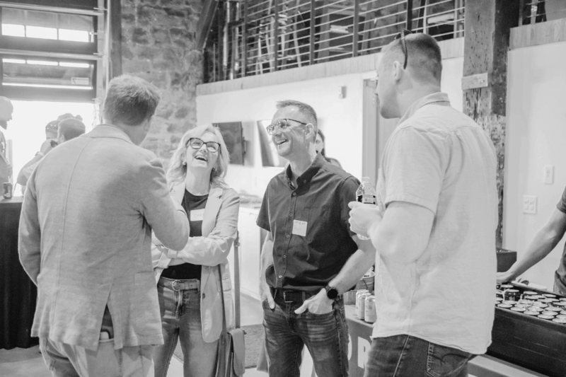 Lon Stroschein and Vintage One member Frank laughing with other Normal 40 community members at an in-person mastermind meetup