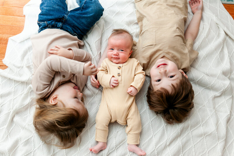 Baby and big brothers laying on floor at lifestyle newborn session in Columbia, SC
