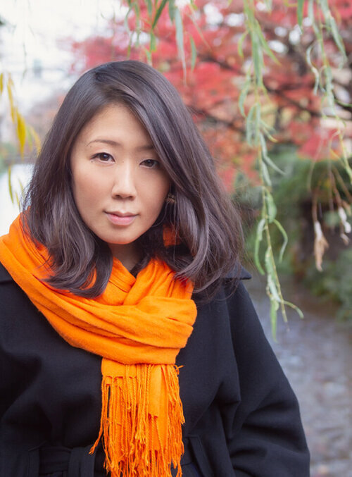 Photographer Chiaki Sato standing outside wearing an orange scarf