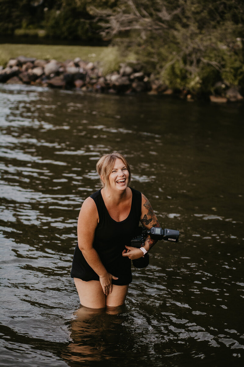 woman smiling standing in a river with camera