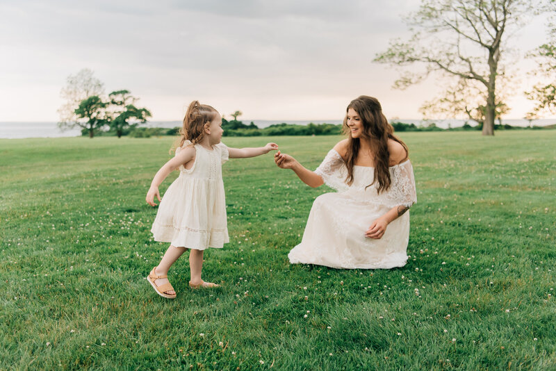 Couple in field, looking down at pregnant mom's belly