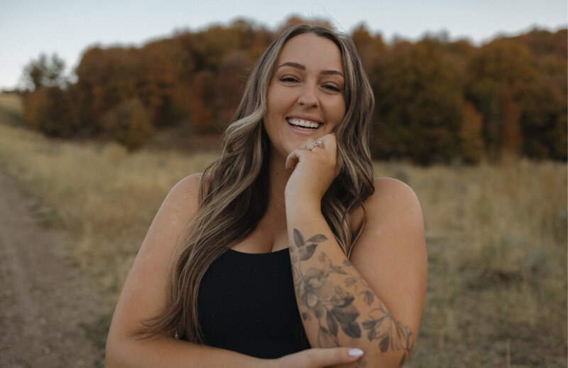 A woman smiling at the camera in an outside setting during Fall in Idaho Falls, ID.