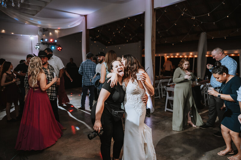 bride hugging and kissing photographer at wedding reception