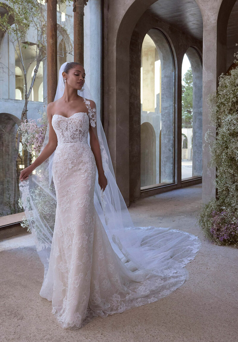 Bride wearing a white sleeveless dress and a long veil posing indoors