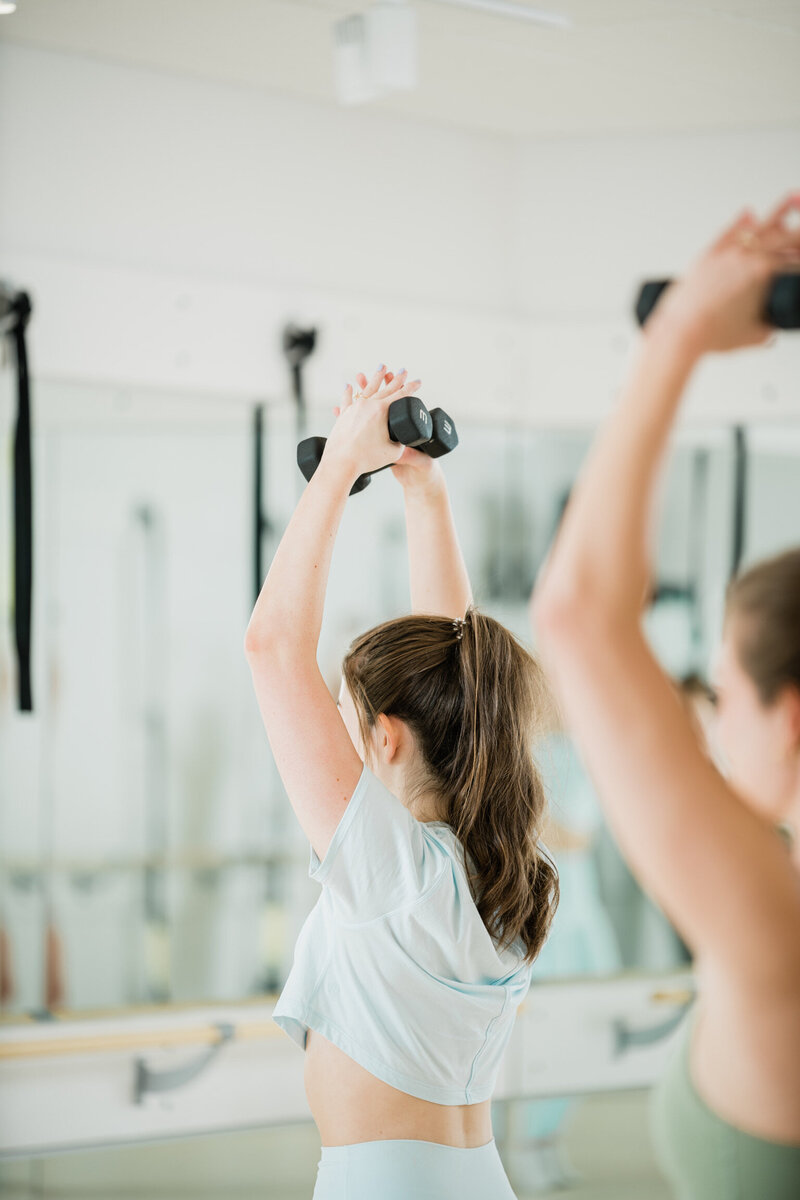 Woman holding dumbbells above her head