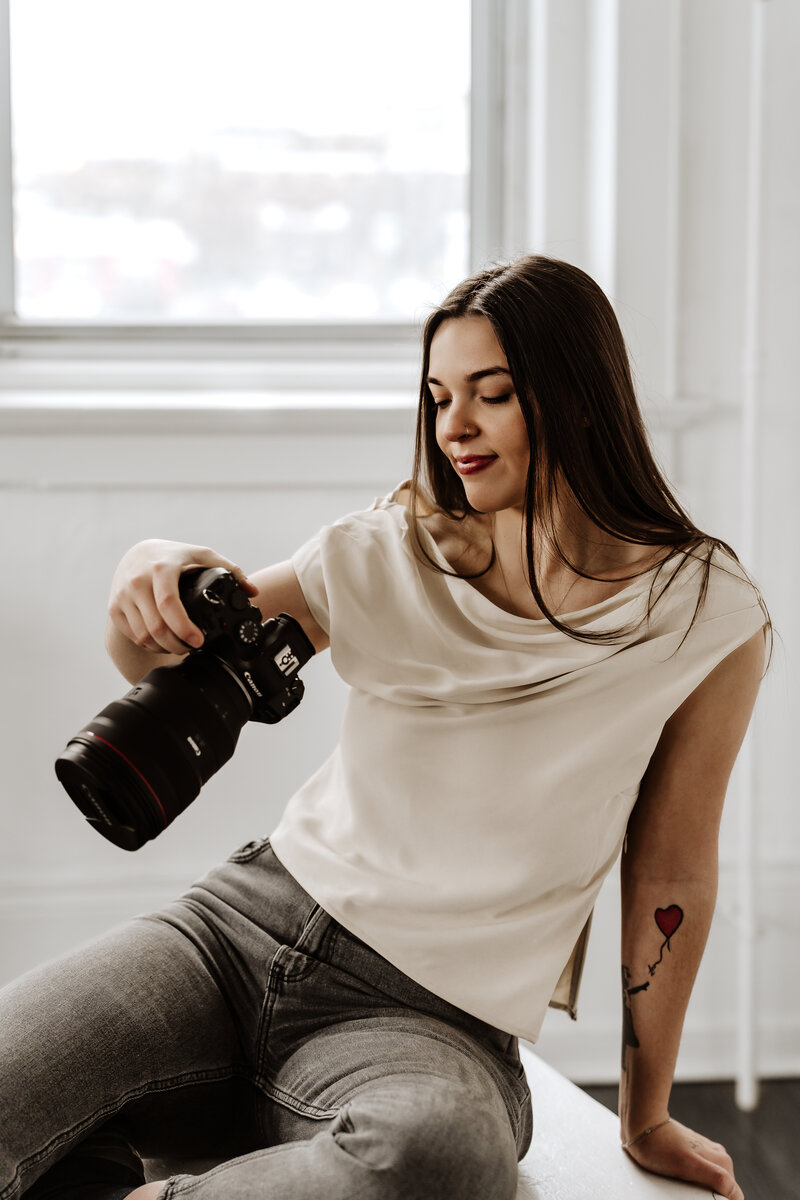Professional female photographer holding camera during branding session in natural light studio – Bedminster, NJ