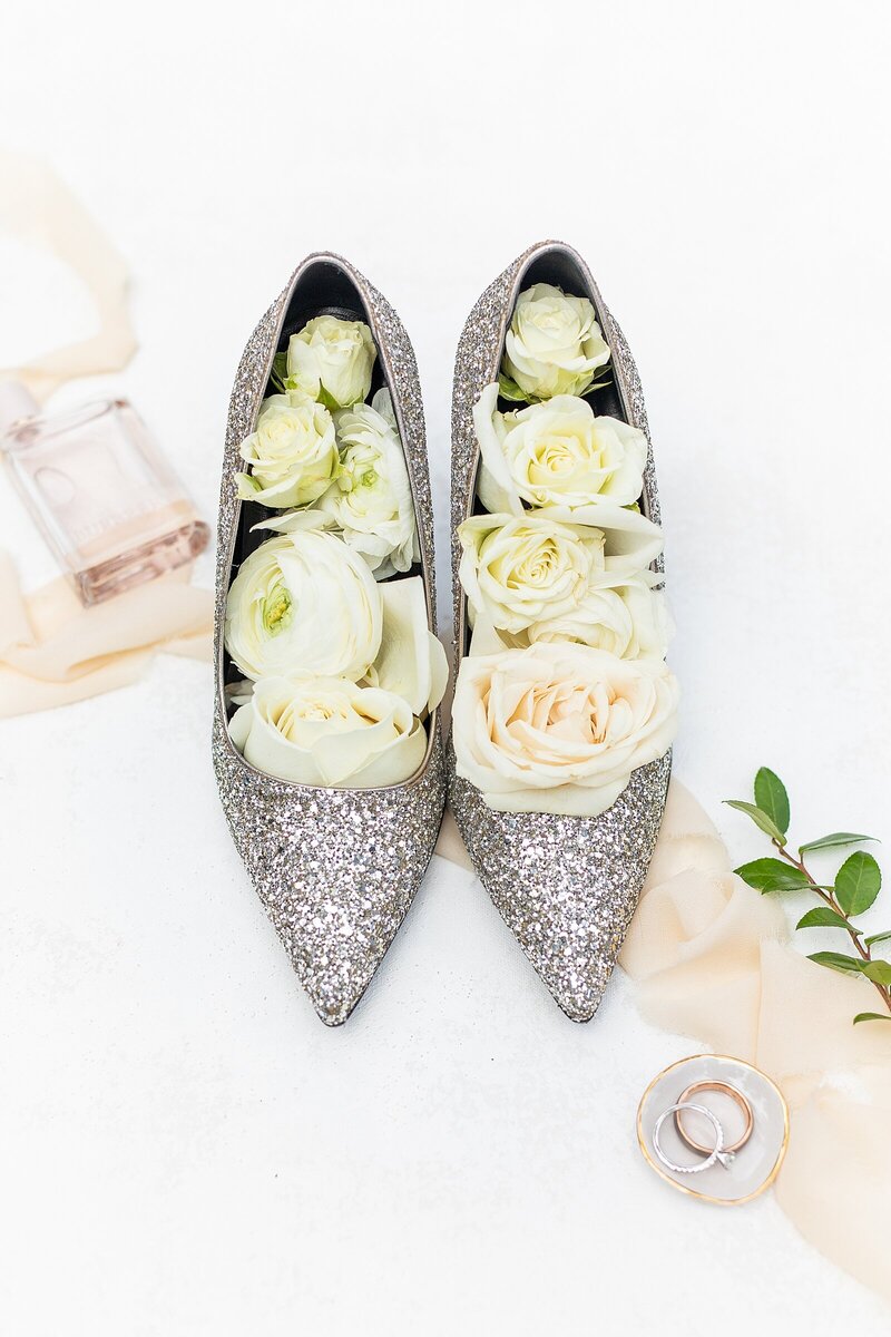 Silver Bride heels filled with white and pink flowers, Burberry perfume, wedding band, and diamond engagement ring at Carlsbad Windmill by Wedgewood Weddings in Carlsbad, California - Sherr Weddings