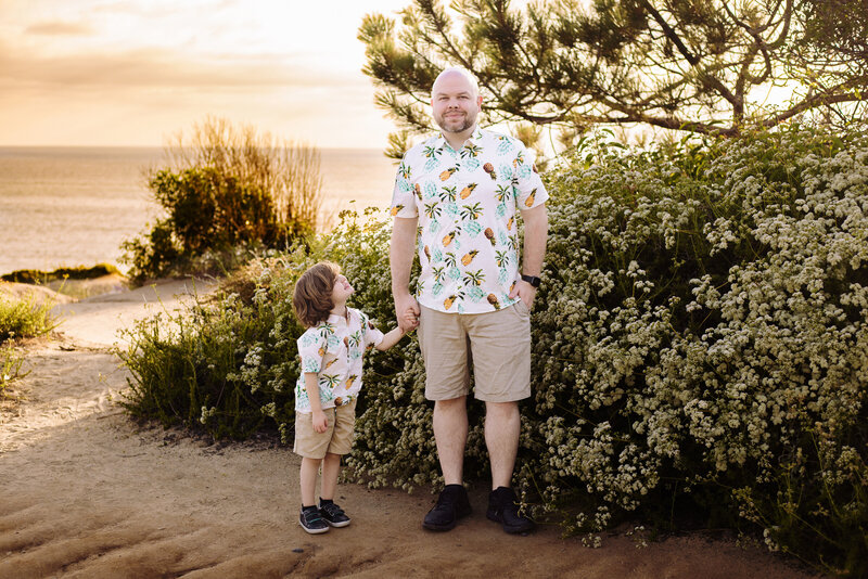 family photographer, a dad holds his sons hand at the beach