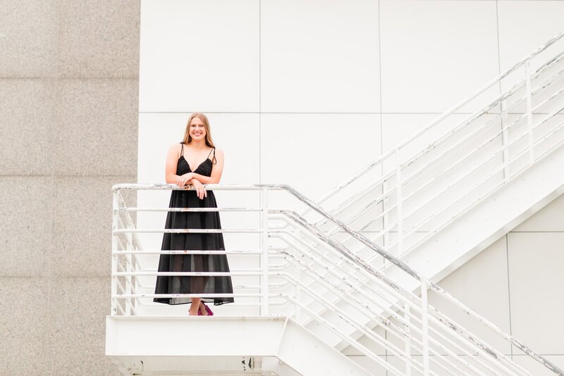 a girl in a black dress posing on a staircase