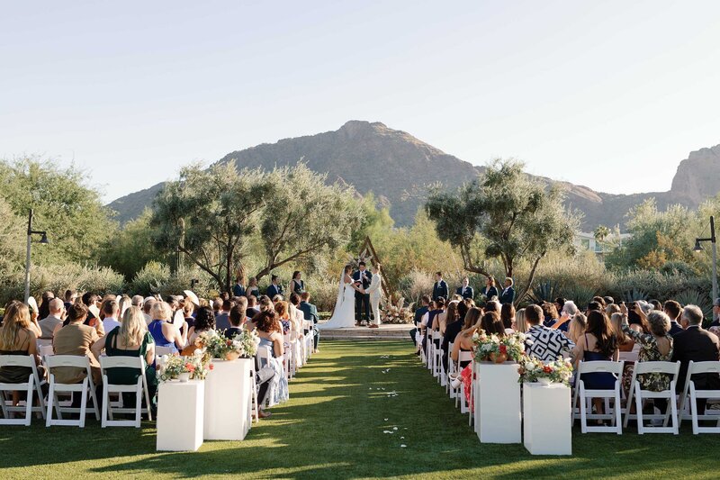 Scottsdale wedding ceremony on an outdoor lawn with desert mountains in the background.