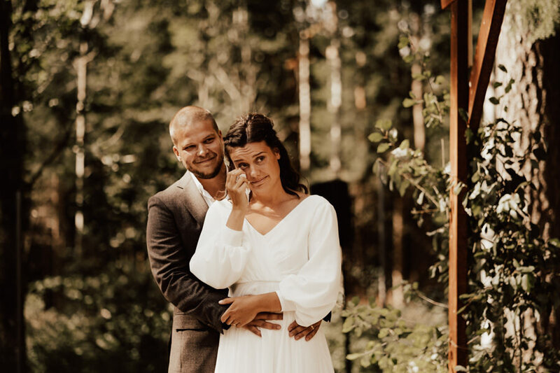 lesbiskt queer par med blomsterkransar håller om varandra och skrattar under bröllopsfotografering