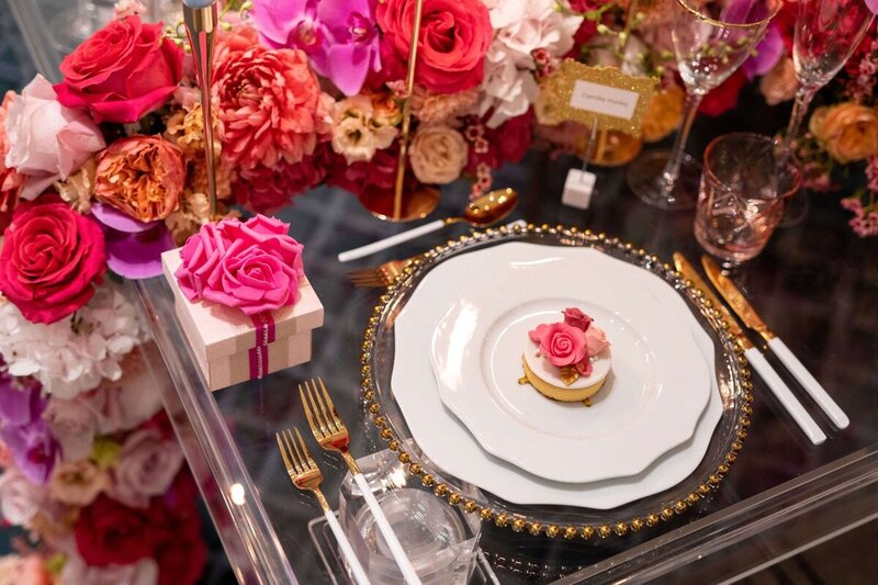 Luxury table setting with gold beaded charger plate, fine china decorated with pink and gold flower arrangements complimented with a rose box favour with a luxury biscuit with pink sugar flowers