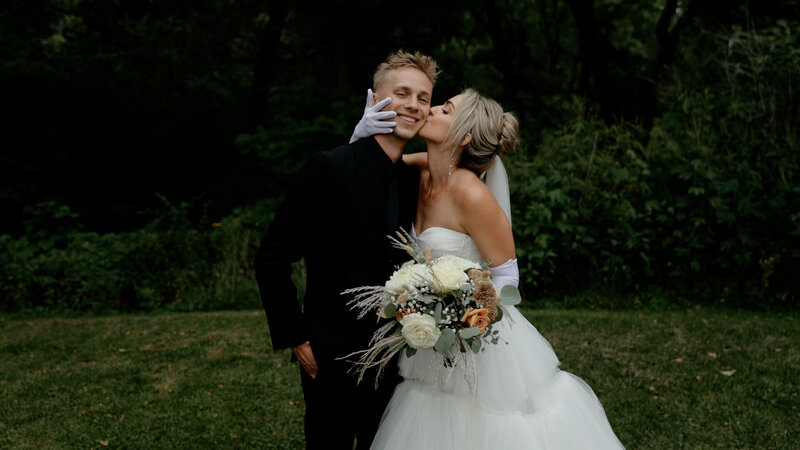 Iowa Wedding Videographer Wife kisses husband on cheek at backyard wedding in Iwoa
