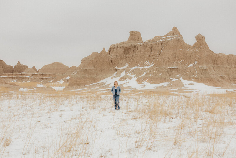 Girl standing in front of badlands rock formations.