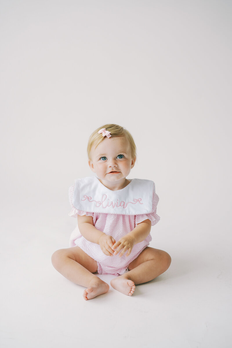 one year old girl touching cake during a cake smash milestone session