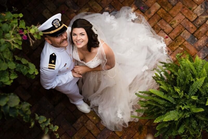 groom in uniform and bride in her wedding dress on a brick floor