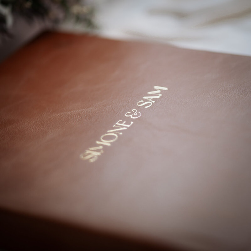 Close up of custom debossed names on the front of a tan leather wedding album