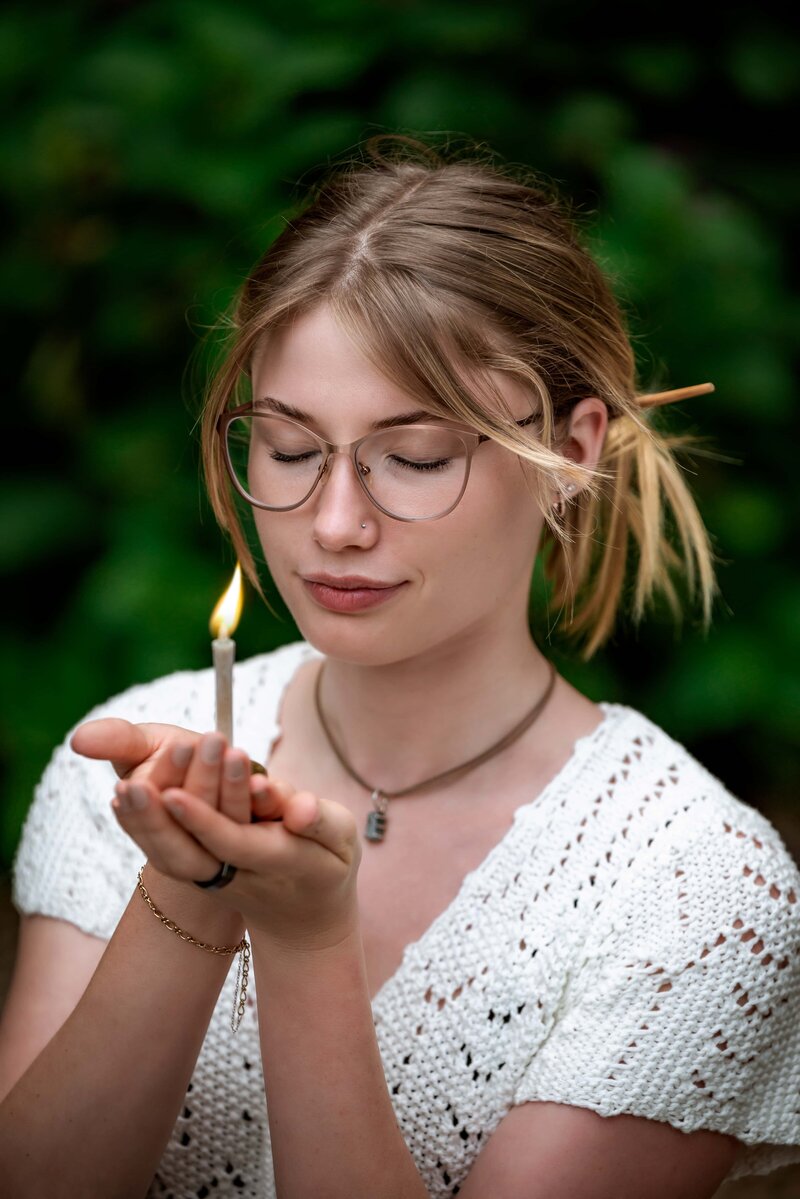 Naturopath holding meditation candle with her eyes closed