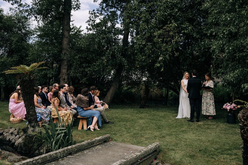 an intimate backyard wedding ceremony in merivale on lawn by a bridge over a creek