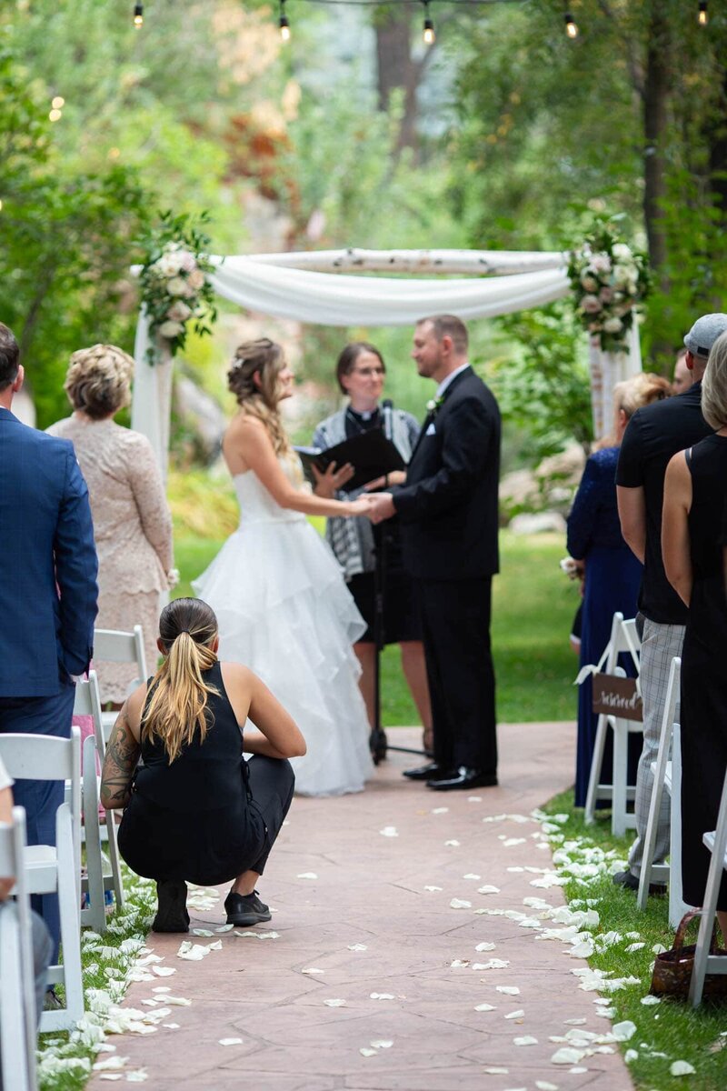 Colorado wedding photographer crouching in the aisle of a wedding ceremony