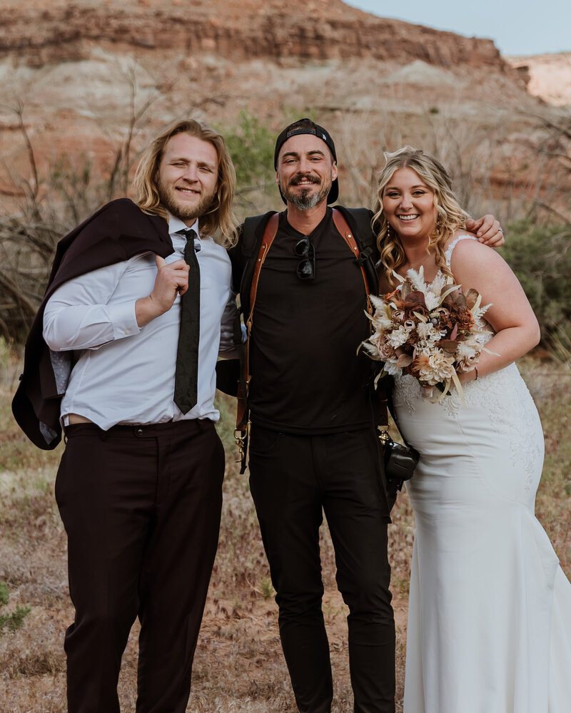 photographer smiling with bride and groom