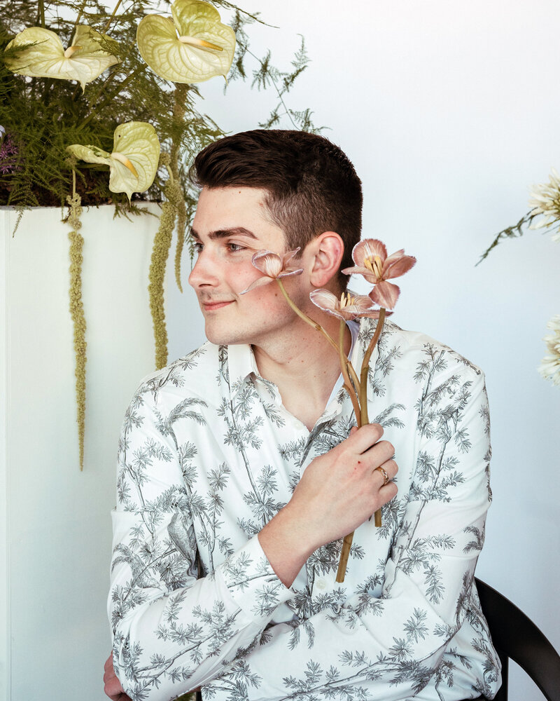 Cole Buys holding pink flowers, floral background.