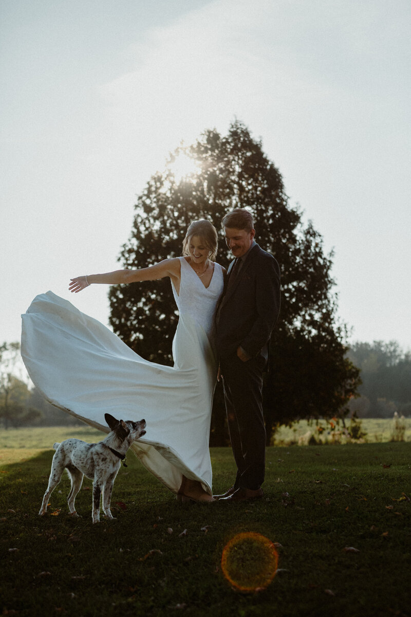 wedding portrait of a couple with their dog at sunset
