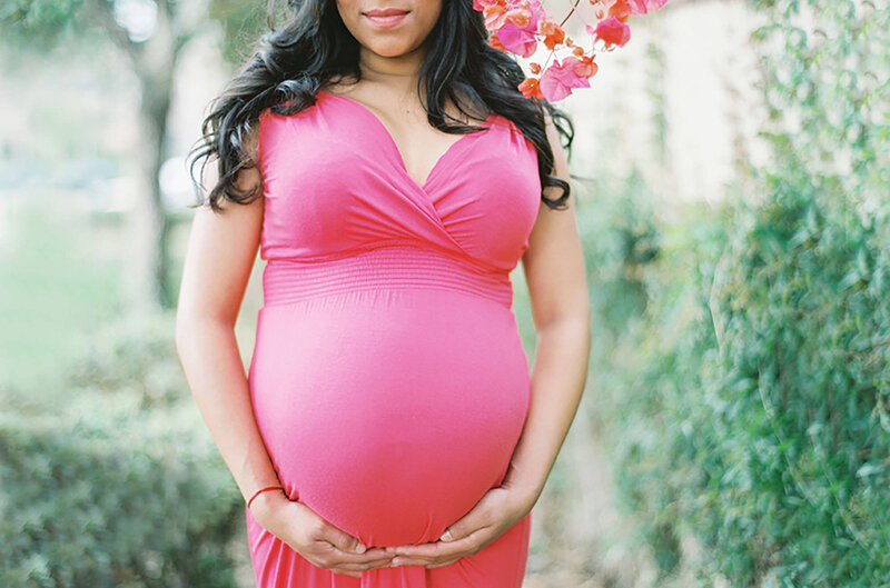 A close up photo of a mom-to-be's belly  who is wearing a pink dress