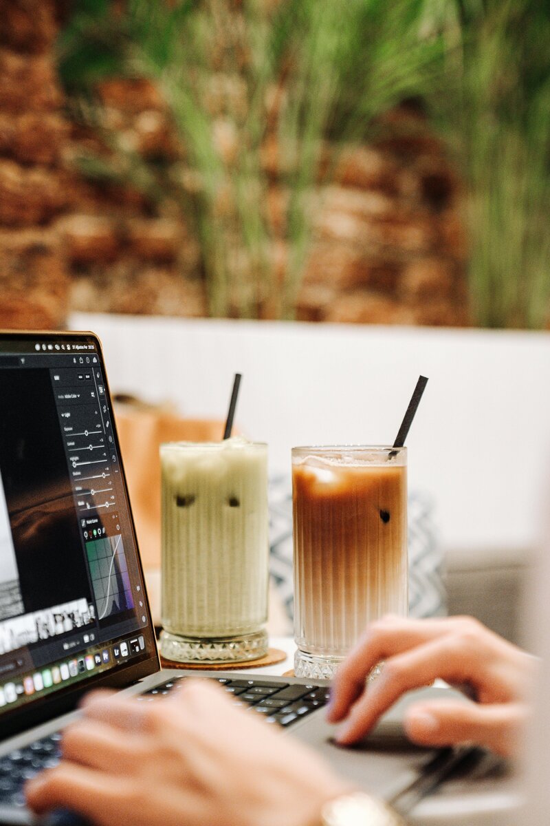 Working remotely with iced coffee and laptop in a lush café setting