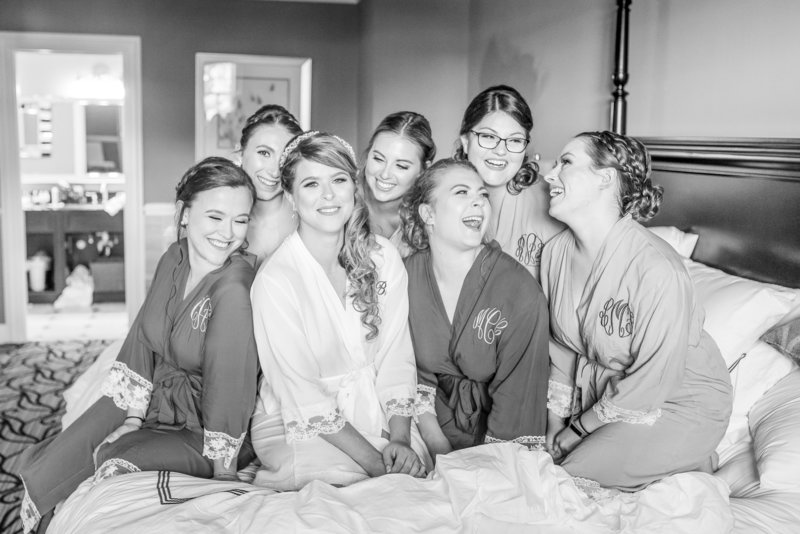 Bride and her girls capture a laughing photo on the bed.