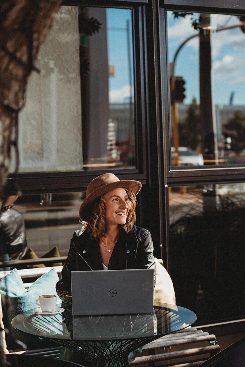 Personal branding image of female CEO working on her laptop in a coffee shop
