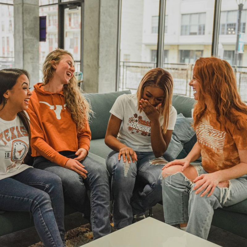 A group of University of Texas girls laughing wearing game day apparel