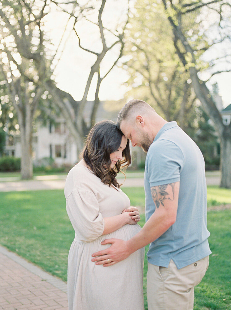 Expectant mom and dad, snuggling her new bump on a beautiful spring day in Edmonton