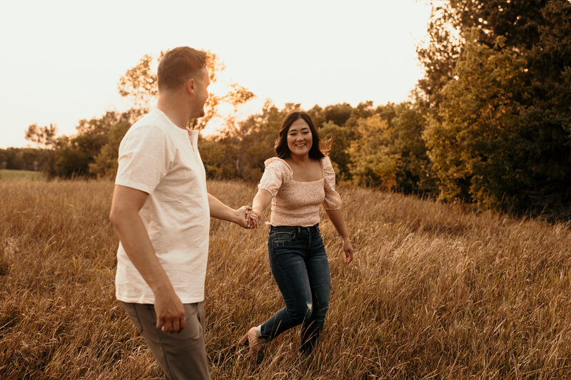 couple running through field at sunset
