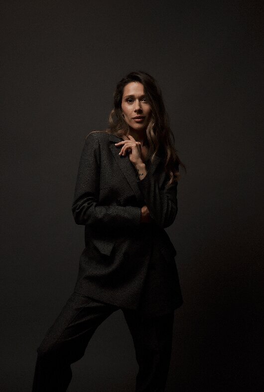 dark and moody business portrait in the studio of a woman wearing a dark wool suit
