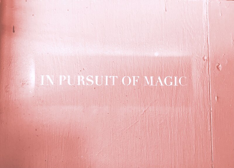 Pink background with quote in white writing that says in pursuit of magic