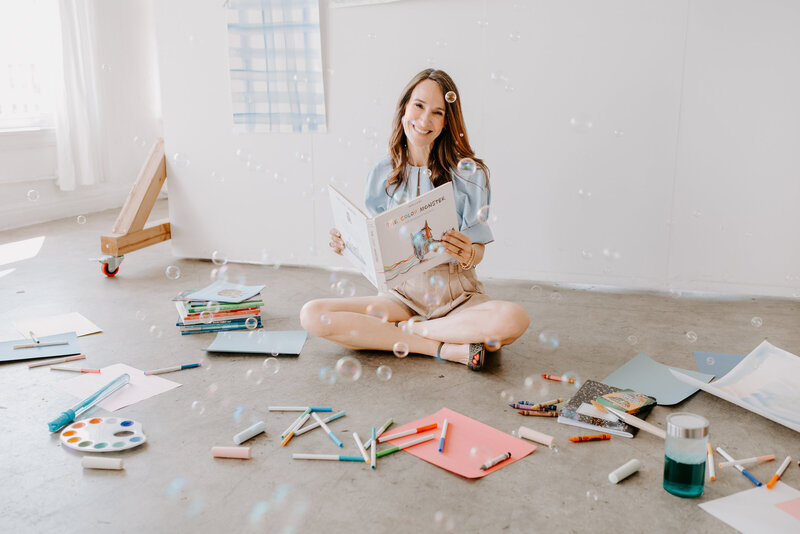 Child therapist sits on the floor, surrounded by supplies