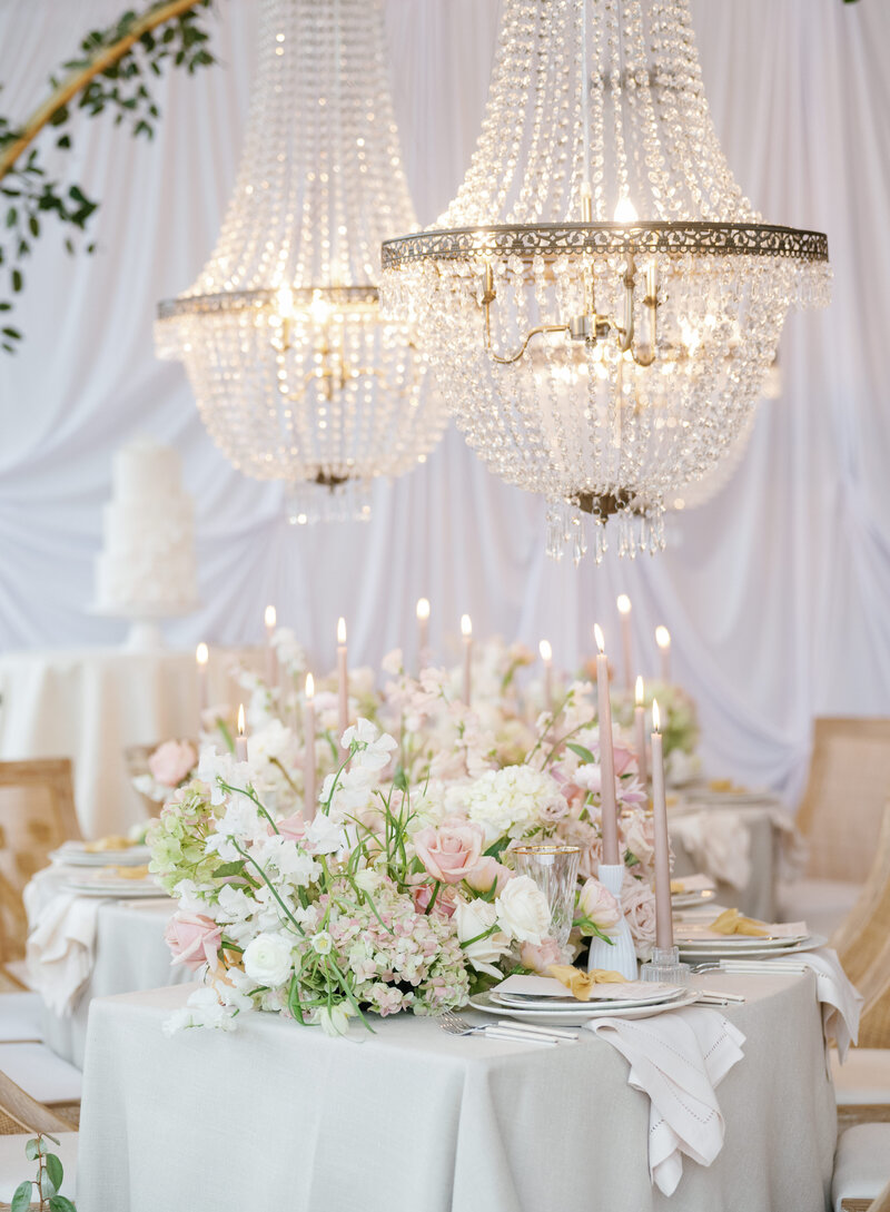 Chandeliers and white and pink flowers with candles at a luxury wedding reception at Venue3Two