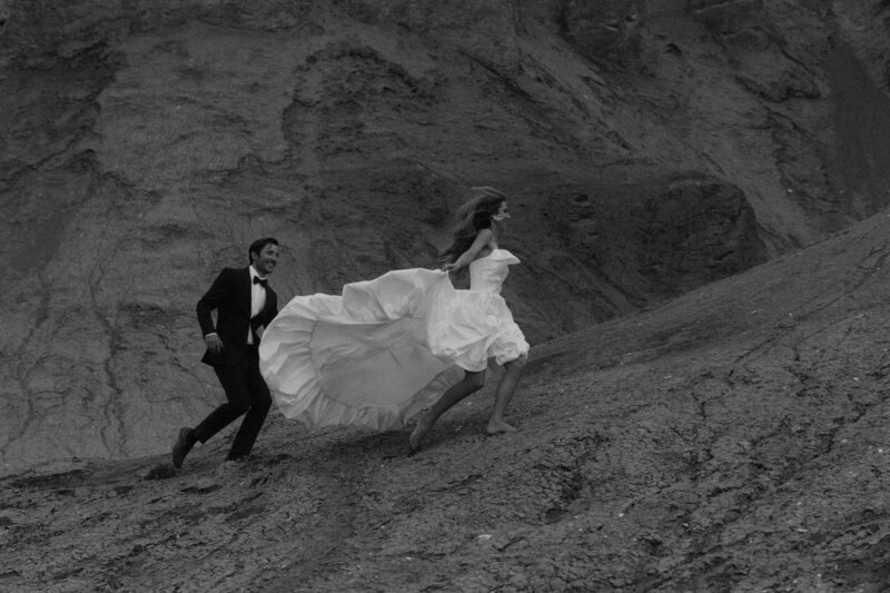 Bride and groom running in desert near lake powell