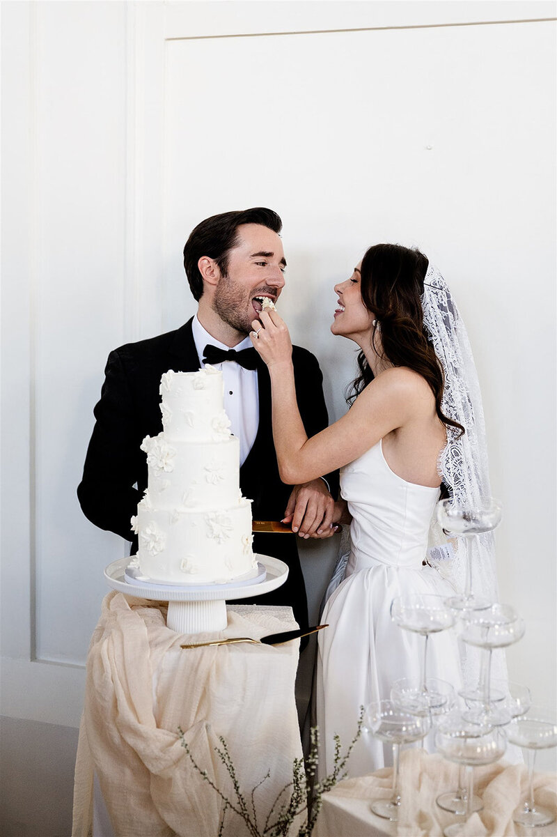 bride feeds groom a piece of wedding cake after their wedding ceremony